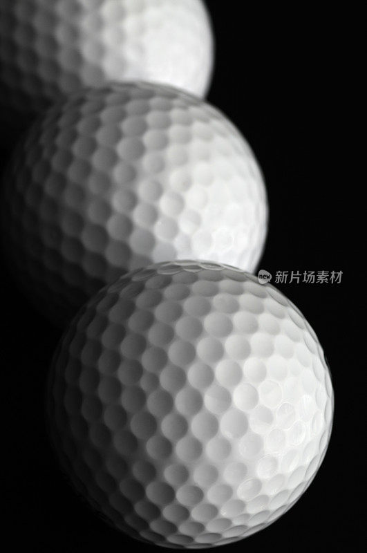 三个高尔夫球在一个垂直行和黑色背景