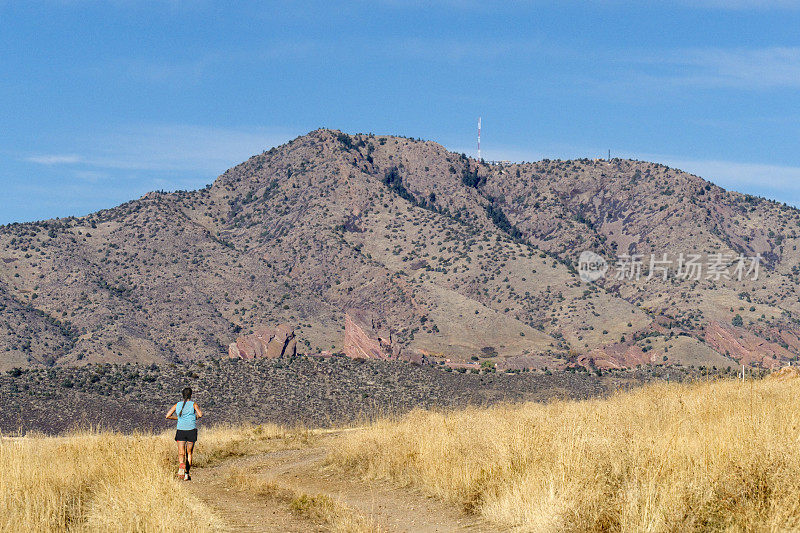 年轻女子沿着科罗拉多大草原奔向落基山脉