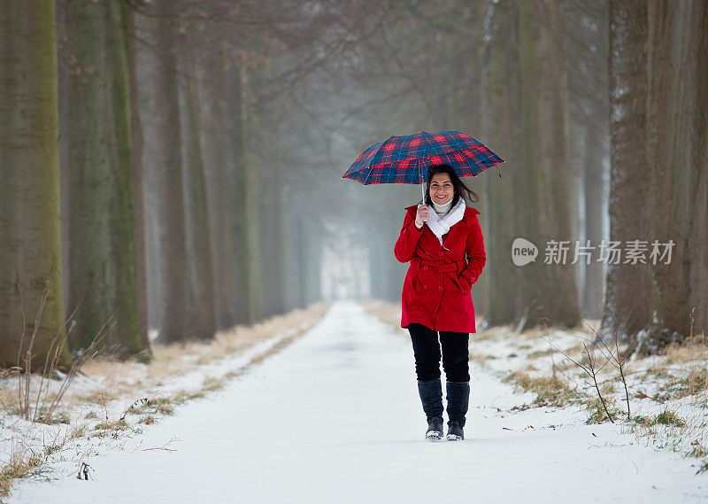 带着伞在雪中行走的女人