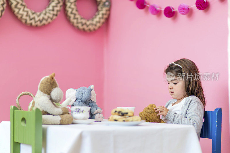 小女孩在茶话会上带着毛绒玩具看起来很伤心
