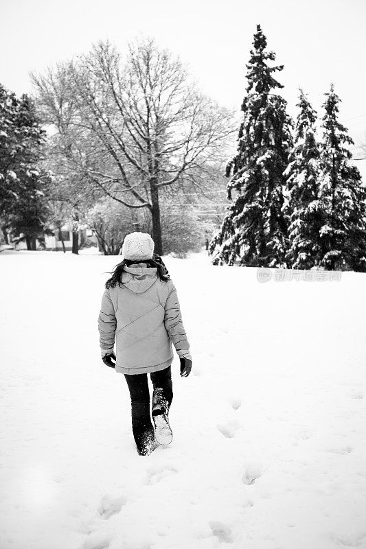 小女孩走在雪中走向树