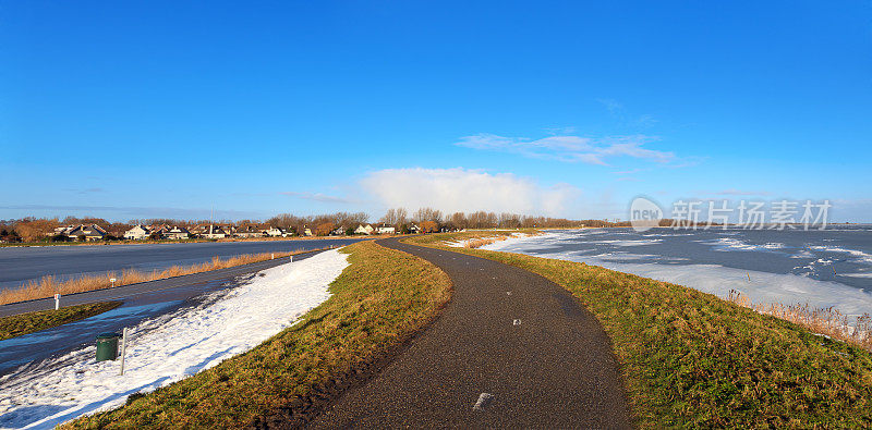 荷兰莫尼克丹冰冻的IJsselmeer湖边的自行车道