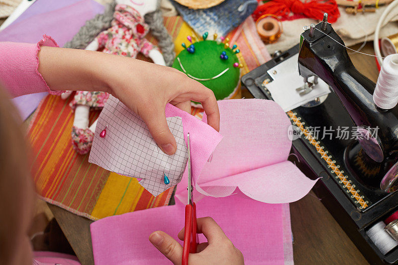 女孩缝制娃娃衣服，俯视图，缝纫配件俯视图，裁缝工作场所，许多对象的刺绣，手工和手工艺品