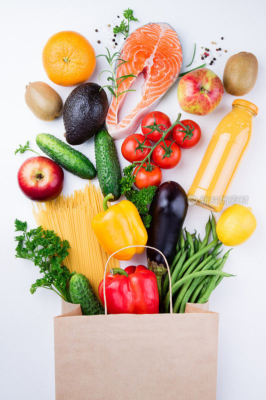 健康饮食背景。健康食品在满纸袋不同的产品鱼，蔬菜和水果在白色的背景