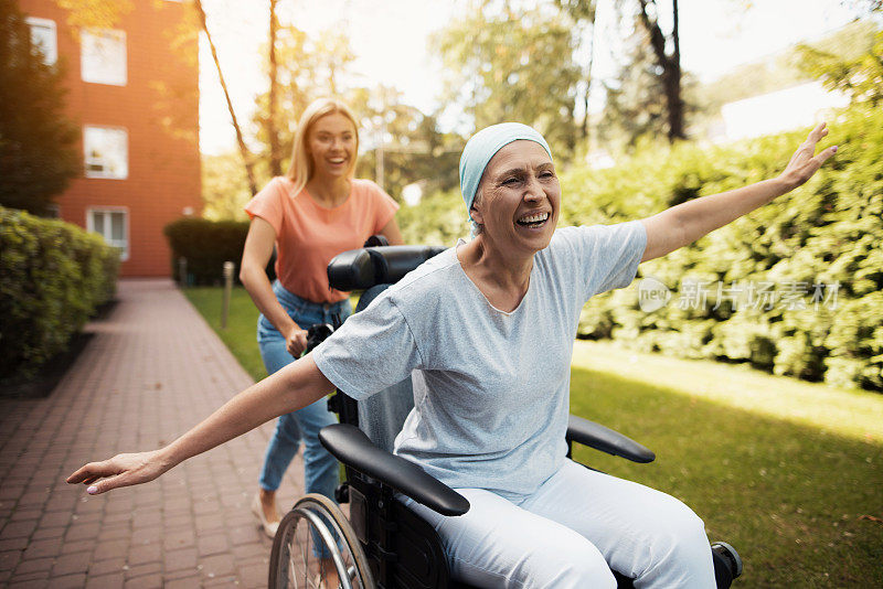 一位身患癌症的妇女正坐在轮椅上。她和女儿在街上闲逛。