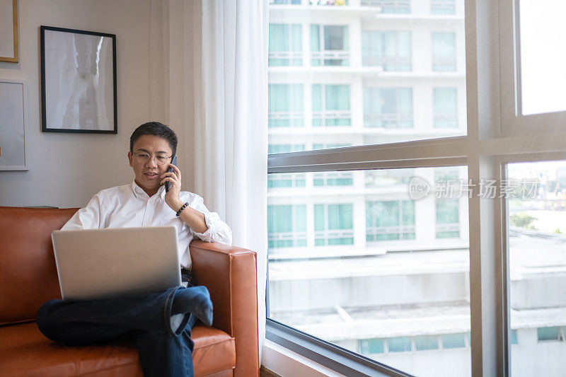 中年中国成年人在家工作，坐在沙发客厅里讲手机