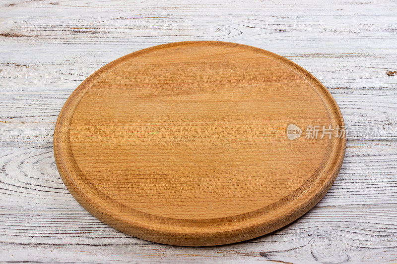 木制的圆形空板比萨饼在木头桌子的背景，俯视图。菜单，食谱或任何菜肴的模型。垂直的图像