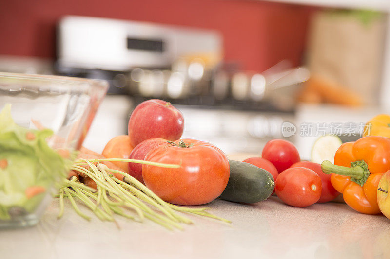 厨房柜台上有水果和蔬菜，还有沙拉。