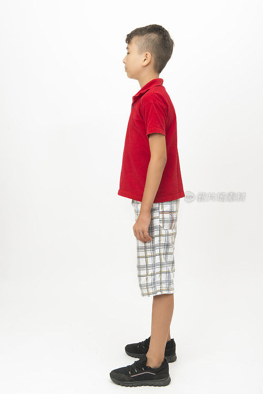 小男孩的侧面视图，站在白色的背景看走开与空白的面部表情