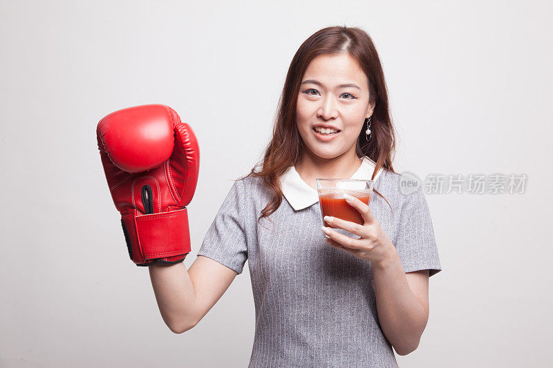 拿着番茄汁和拳击手套的年轻亚洲女人。