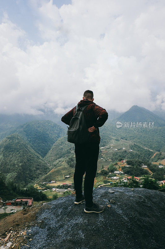 在越南，一名男子正在欣赏梯田和山脉的景色