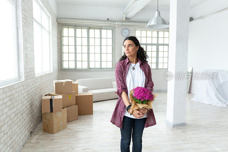 中年妇女搬进新公寓，手里拿着花