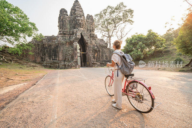 柬埔寨古庙建筑群里骑自行车的年轻女子