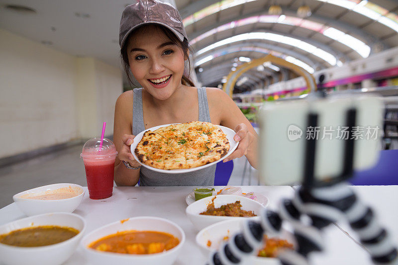 年轻美丽的亚洲女游客在餐厅享受印度美食的肖像