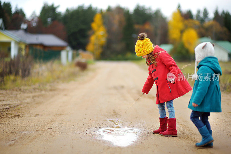 美丽的秋日，两个可爱的小妹妹在水坑里玩耍