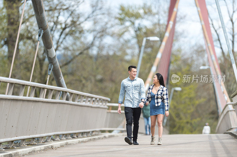 大学时代的亚洲夫妇手牵手过桥