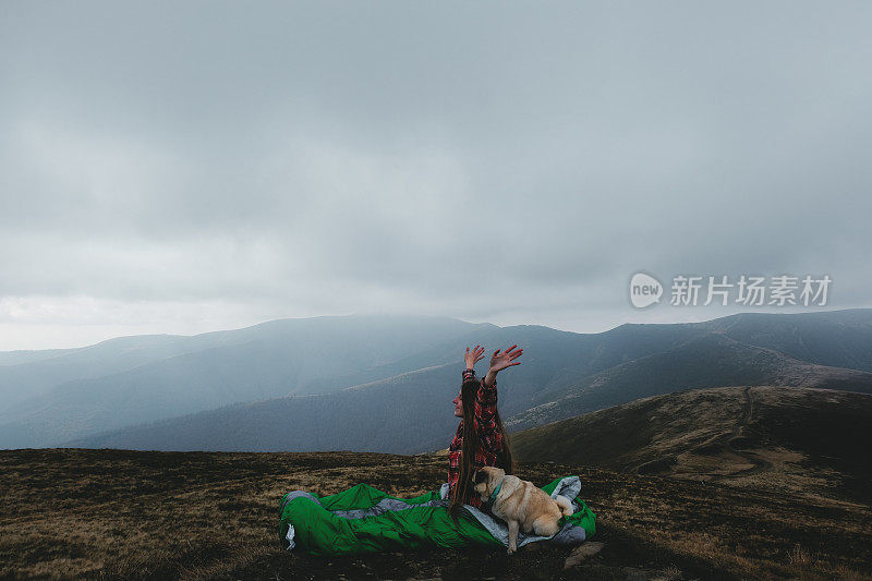 睡袋里的女人和狗在山中醒来