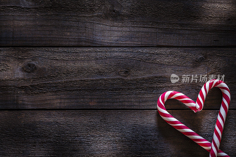 圣诞背景:两根拐杖糖在质朴的木桌上做成一颗心