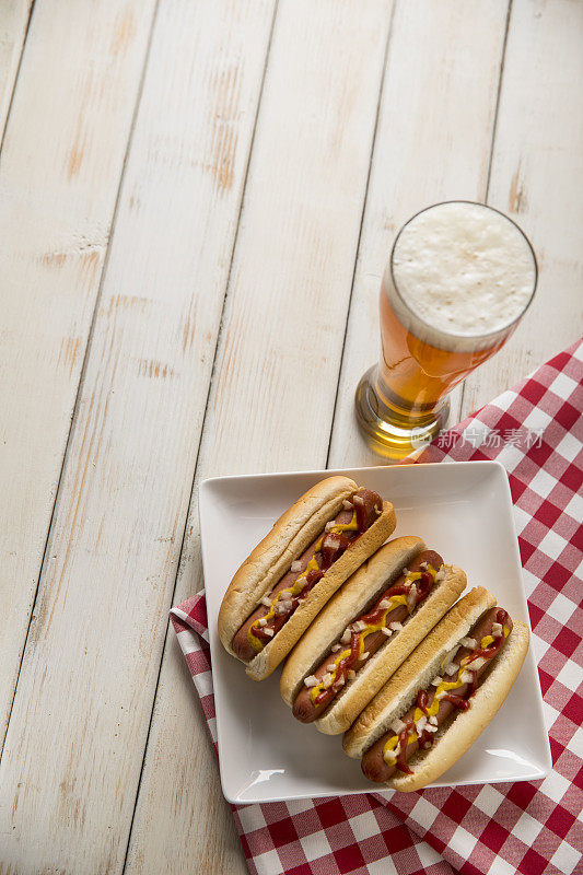 白色长凳上的热狗野餐，啤酒和棒球