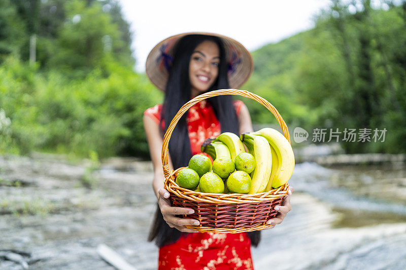 美丽的中国女人拿着一个装满香蕉和酸橙的篮子