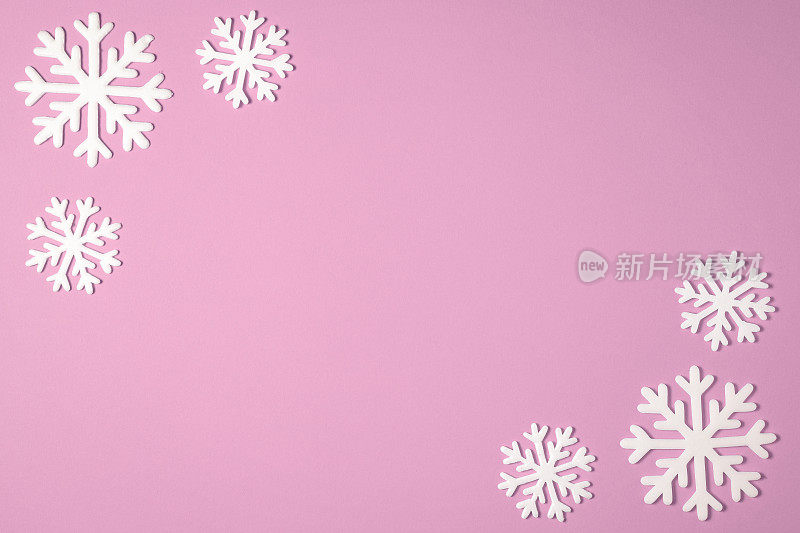 粉红色背景上的圣诞雪花边框。圣诞节最小的纹理与复制空间。俯视图