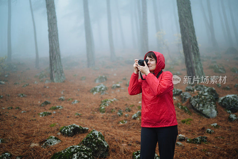 女摄影师拍摄森林中的雾