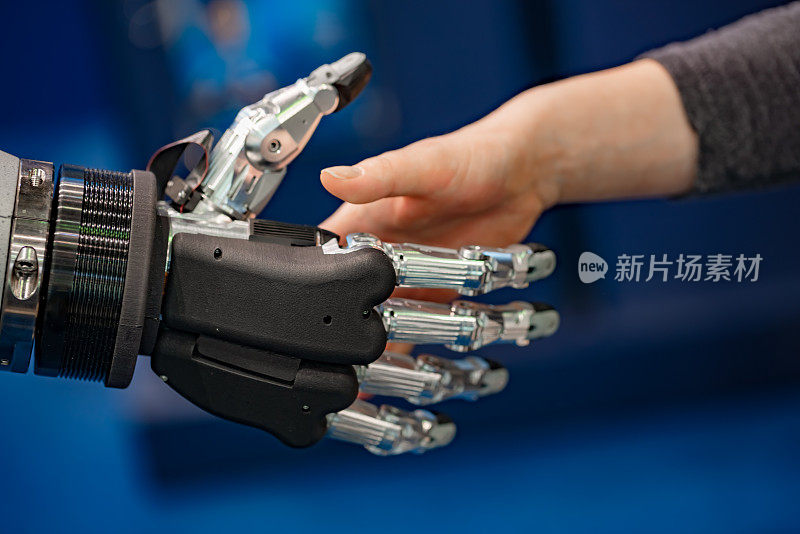 一个女商人和一个机器人握手的手。