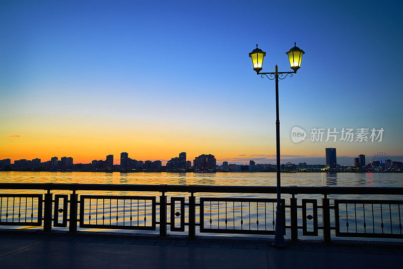 日落时码头的剪影，河流，灯柱