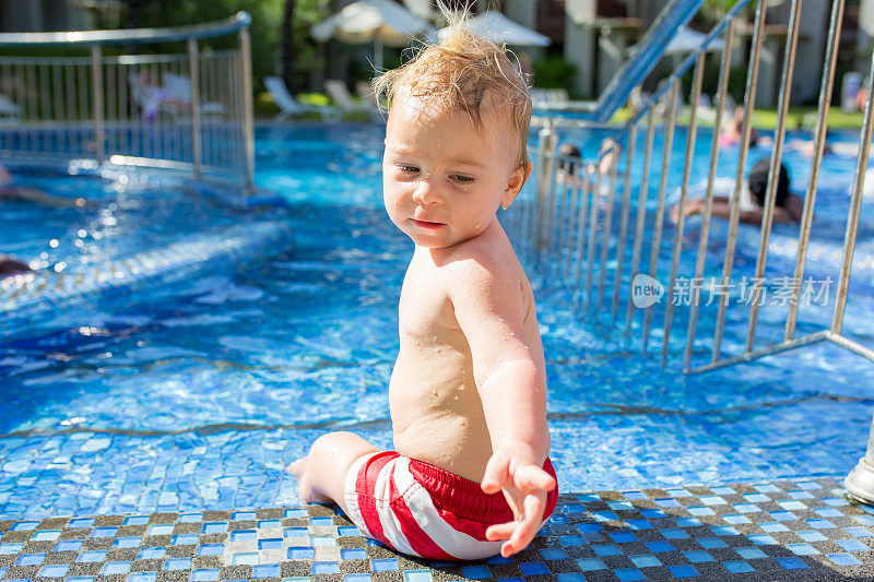 可爱的快乐的小男孩，蹒跚学步的男孩，在一个阳光明媚的日子里在游泳池里放松和玩耍
