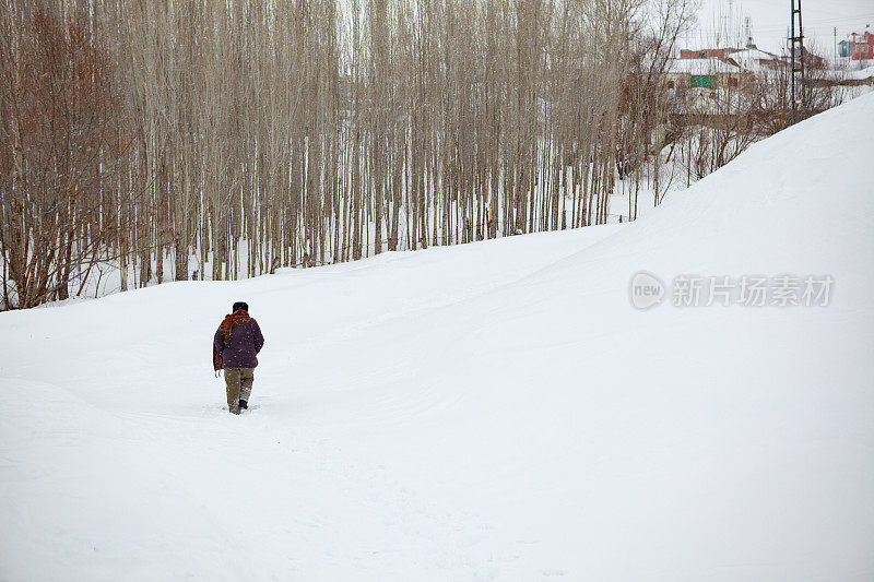 穿着暖和的衣服在雪地上行走的女人