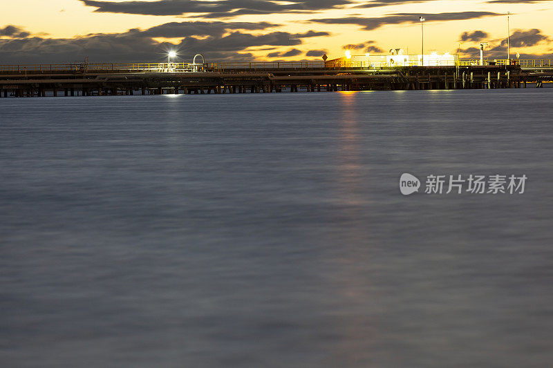 海湾在夜晚与油轮在炼油厂港口和城市天际线，背景与复制空间