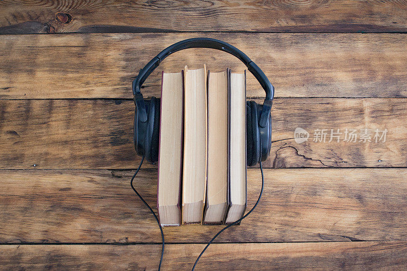 耳机放在木桌上的一堆书上。有声读物。学习通过有声读物