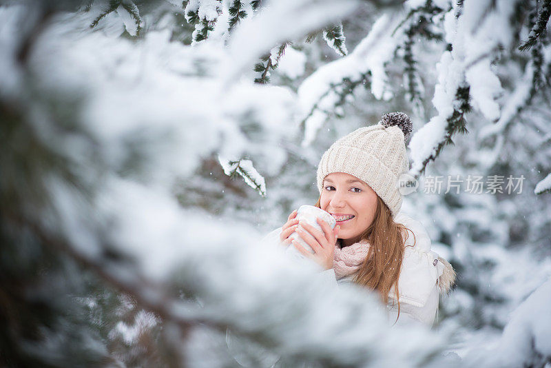 年轻女子喝着咖啡，热巧克力，茶，外面是雪