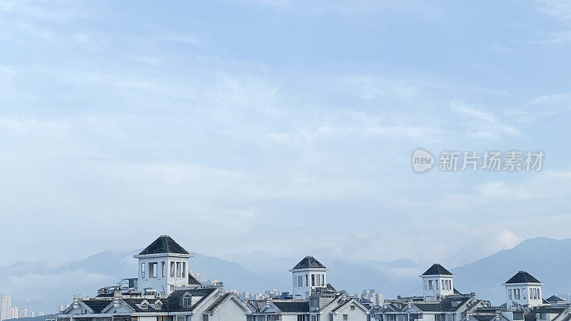 以远山和天空云彩为背景的一排屋顶