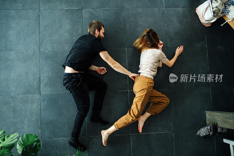 男人抓住女人的腰带作为他们在地板上做的场景的一部分