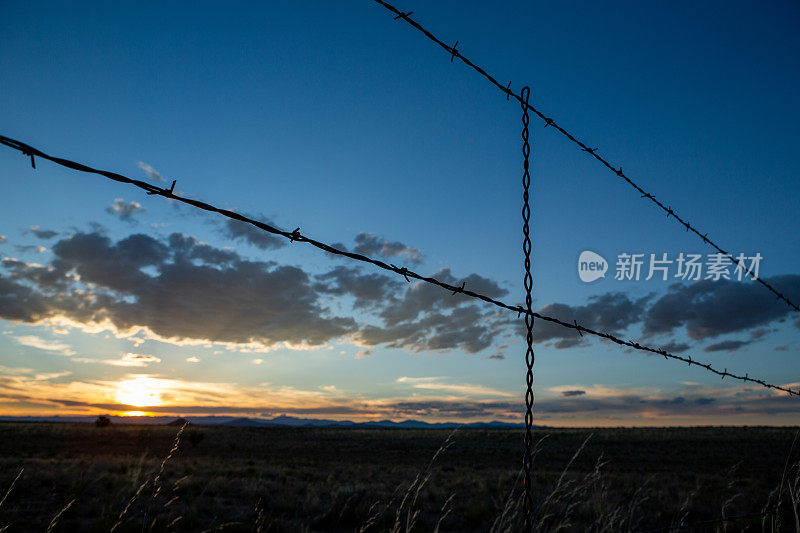 西南的夕阳透过铁丝网在远处与云层在地平线上