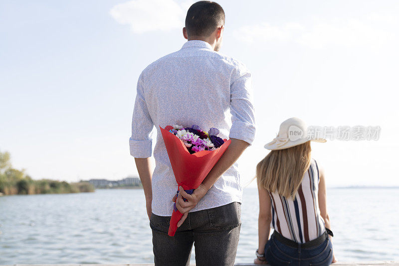 那个快乐的男人在公园里给一个女人送花。一个男人在一个夏日给他的爱人送花的照片。浪漫的情侣