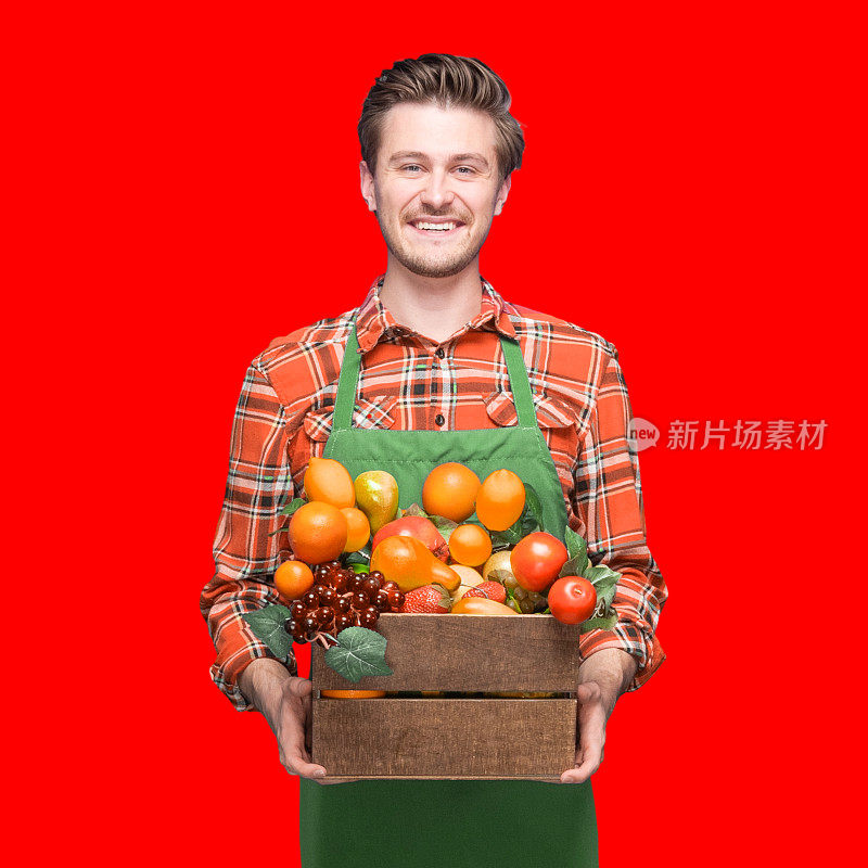 男性农民站在彩色背景，穿着格子衬衫，拿着板条箱