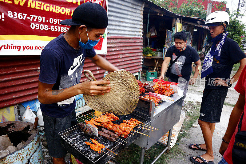 街头小贩在他的临时小吃摊上卖各式各样的烤猪肉和鸡内脏烧烤