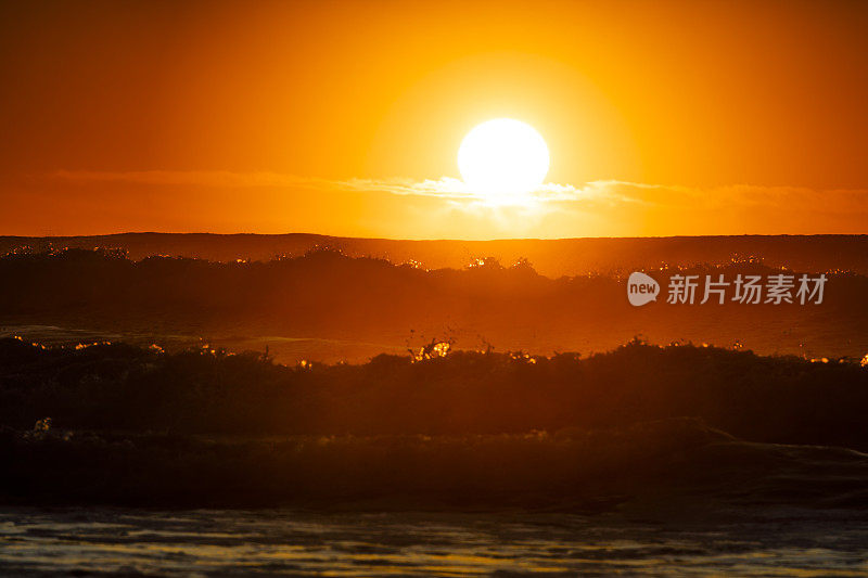 初升的太阳映出浪花的轮廓