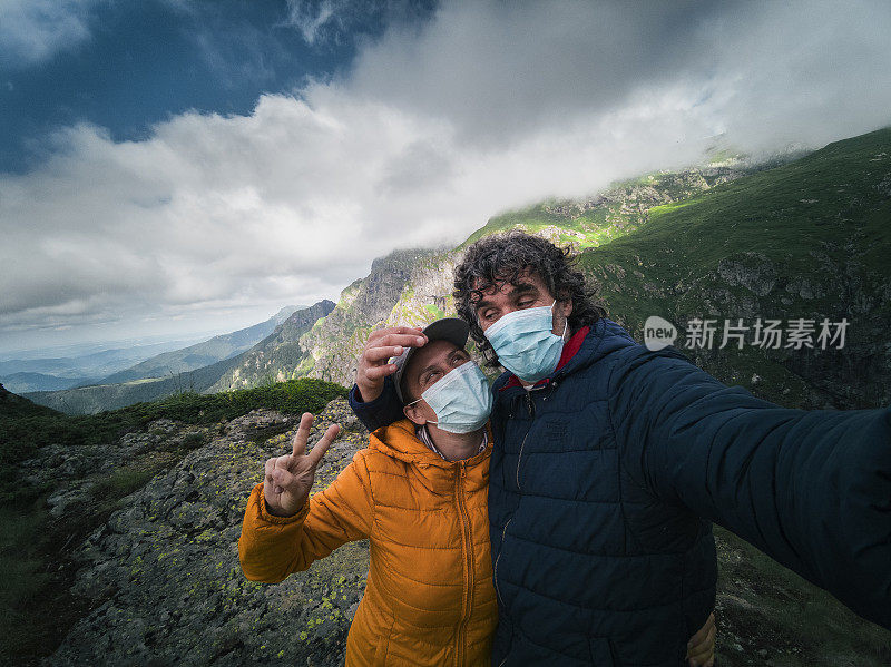 回归自然。新的标准。一对快乐的游客夫妇的肖像戴着防护面具在山上徒步旅行。2019冠状病毒病大流行期间，阳光明媚的户外享受。在社交媒体上问候朋友。