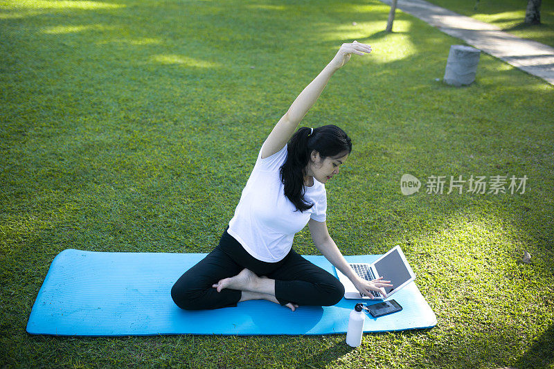 年轻的亚洲孕妇在公园里练习瑜伽