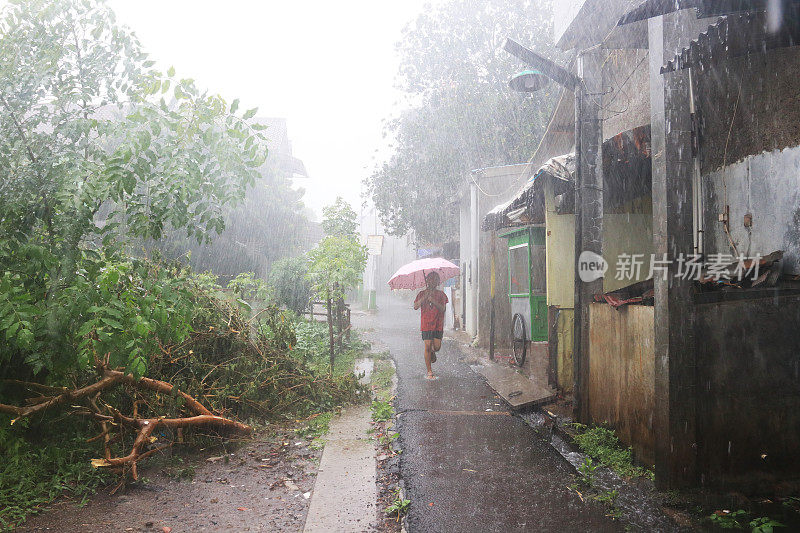 一个小女孩在倾盆大雨中带着雨伞。