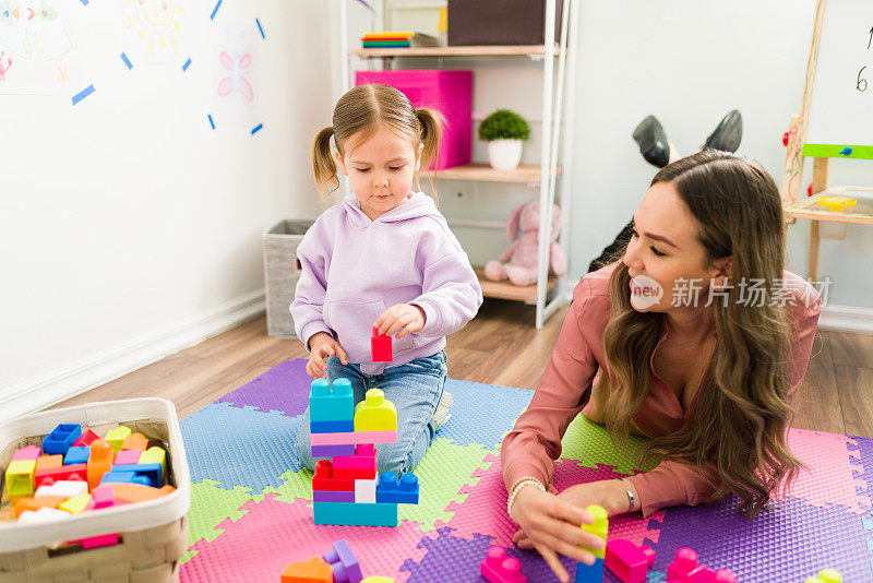 快乐的老师帮助一个小学生用积木搭一座塔