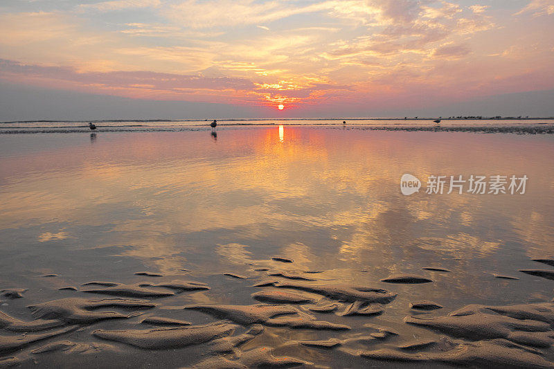 在平静的海面上，夏日日落时沙滩上的涟漪