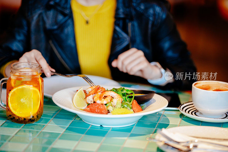 年轻的亚洲年轻女子在餐厅享受新鲜食物的肖像。