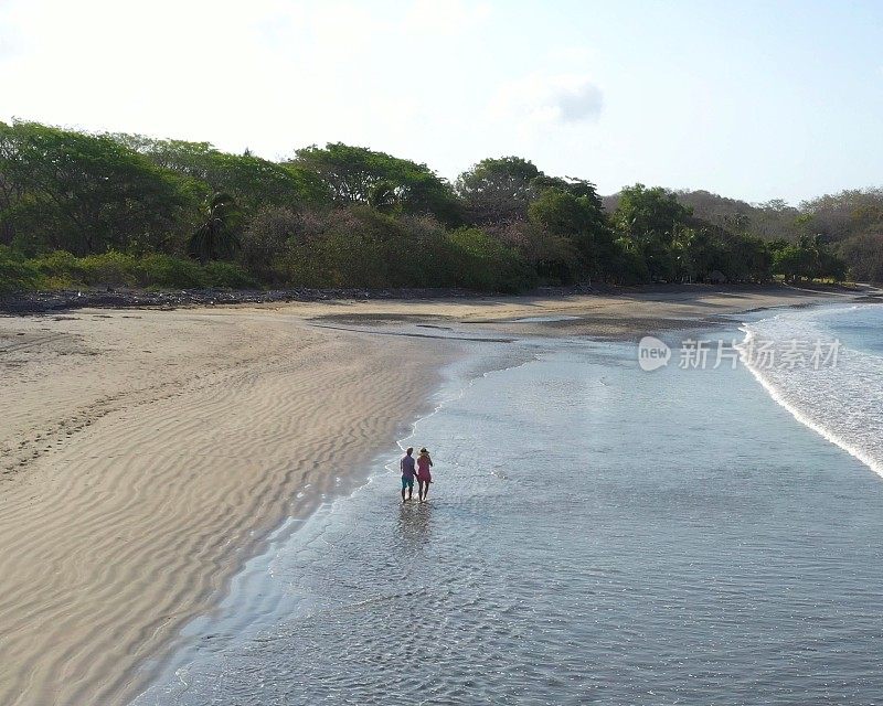 鸟瞰图的成熟夫妇走下海滩在日出