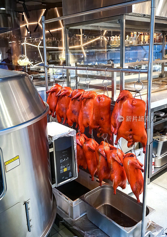 腌渍鸭尸体挂在钩子上，准备在烤箱中烘烤。北京烤鸭。中国菜。
