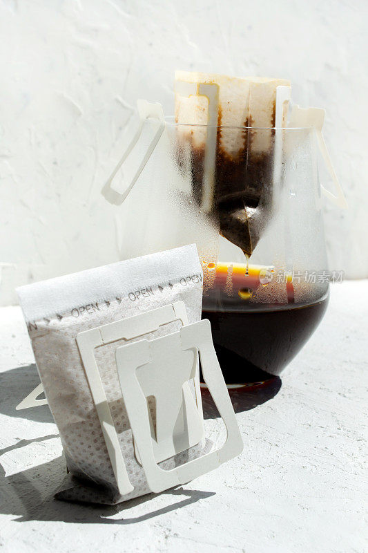 玻璃滴咖啡袋与水滴在白色背景。速溶新鲜晨饮