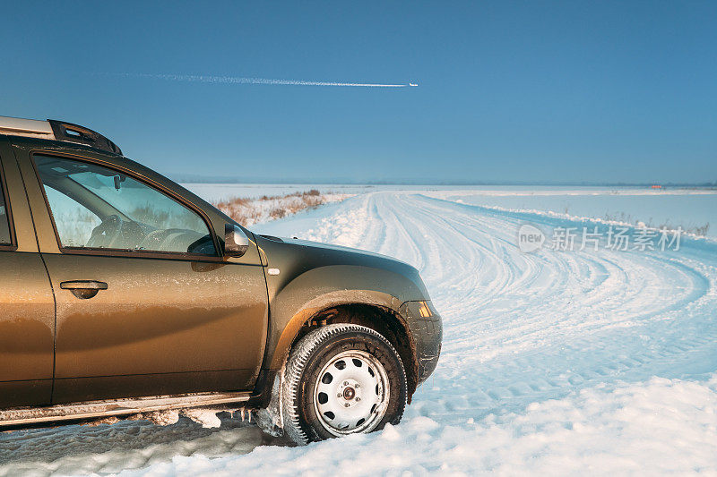 汽车雷诺或达契亚除尘器越野车停在冬季雪原乡村景观。由法国制造商雷诺和罗马尼亚子公司达契亚联合生产的除尘器